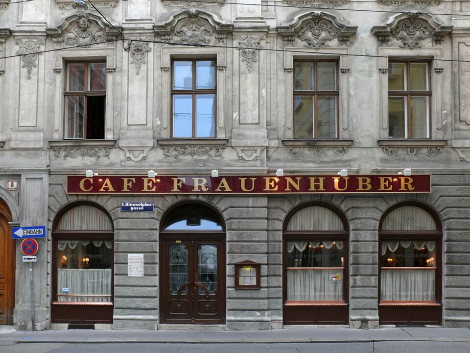 維也納街角一棟米黃色老建築的一樓店面，門楣上以金字寫著 CAFE FRAUENHUBER。